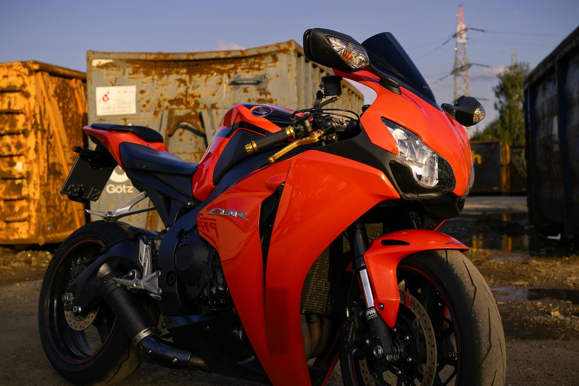 Close-up of a red sport motorcycle parked outdoors in an industrial area.